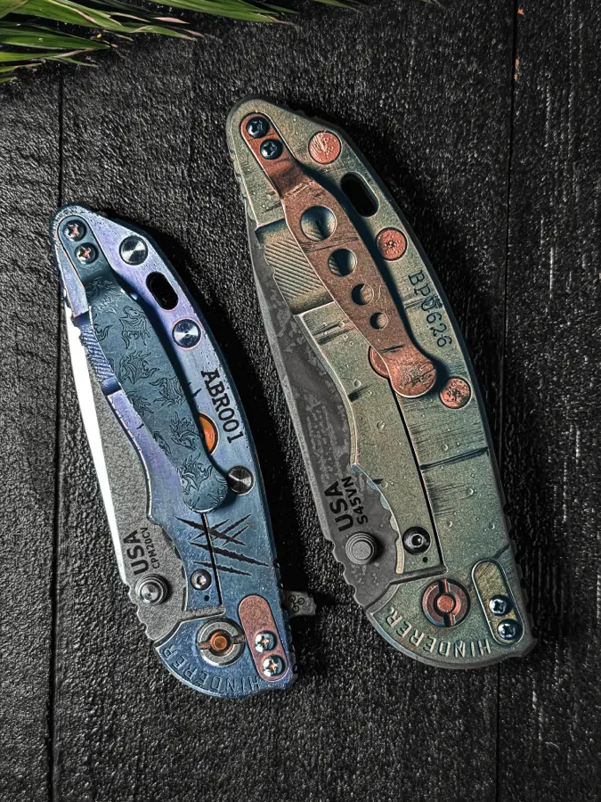 Two customized Hinderer XM-18 folders on black wood