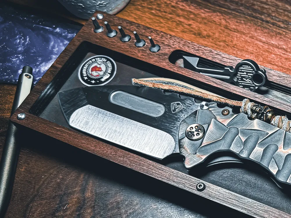 Layer Cake with a large black fixed blade and a rugged paracord wrapped folder in low light