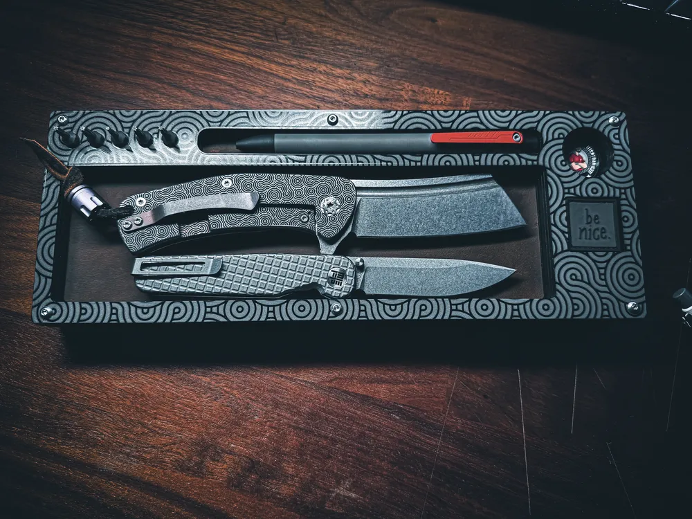 Layer Cake holding a black cleaver style fixed blade with a matching folder and pick