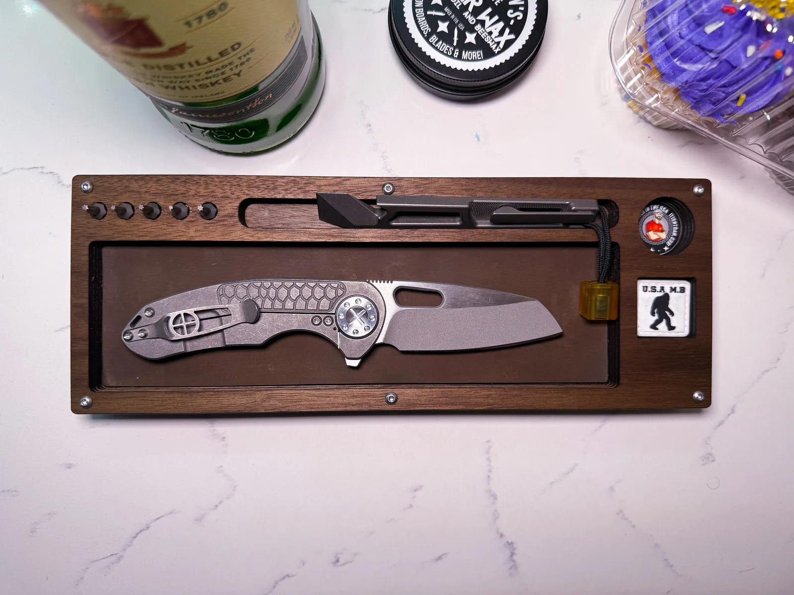 Walnut Layer Cake on a marble counter holding a titanium folder, whiskey bottle behind