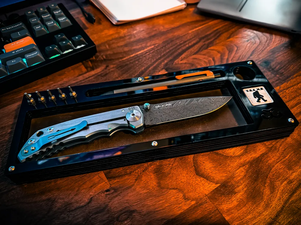 Layer Cake on a warm walnut desk with a blue titanium folder beside a keyboard