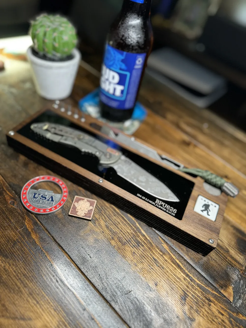 Walnut Layer Cake with a BPU626 folder and pry bar on a plank floor next to a cold one