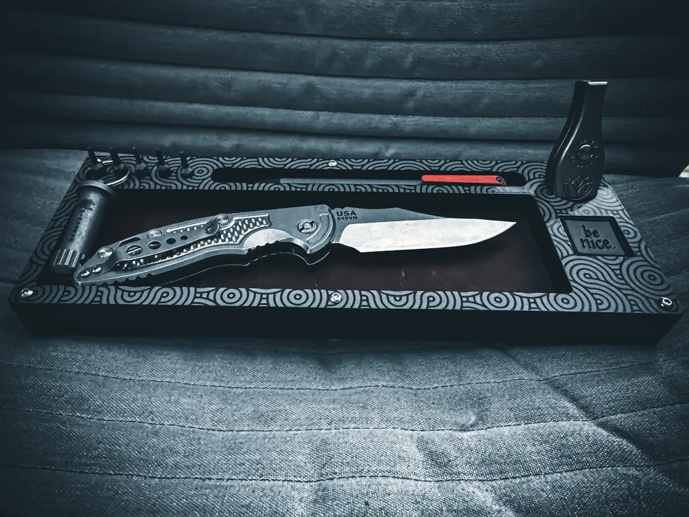 Black Layer Cake with a laser etched pattern holding a folder and fixed blade in cool light