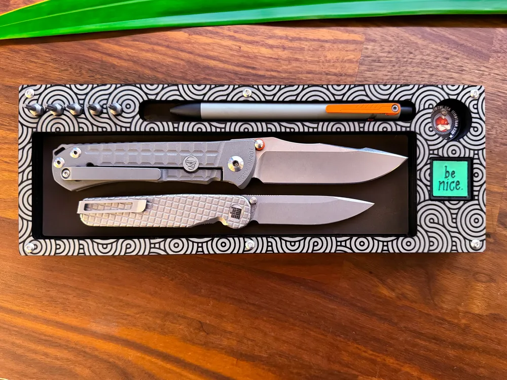Overhead view of a patterned Layer Cake tray with a silver folder and pen knife on walnut