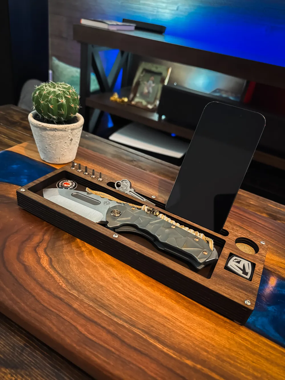 Layer Cake holding a phone upright on a desk next to a cactus
