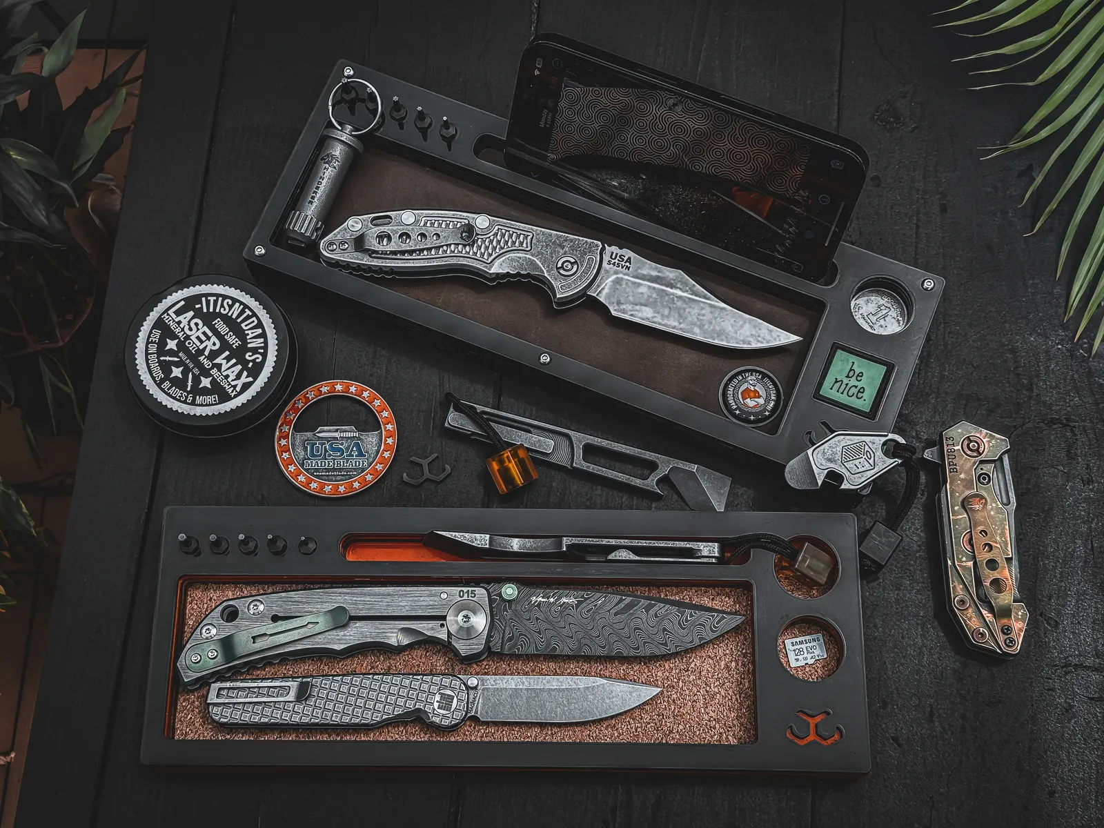 Two Layer Cake trays holding folders, a phone and a full EDC loadout on a dark desk