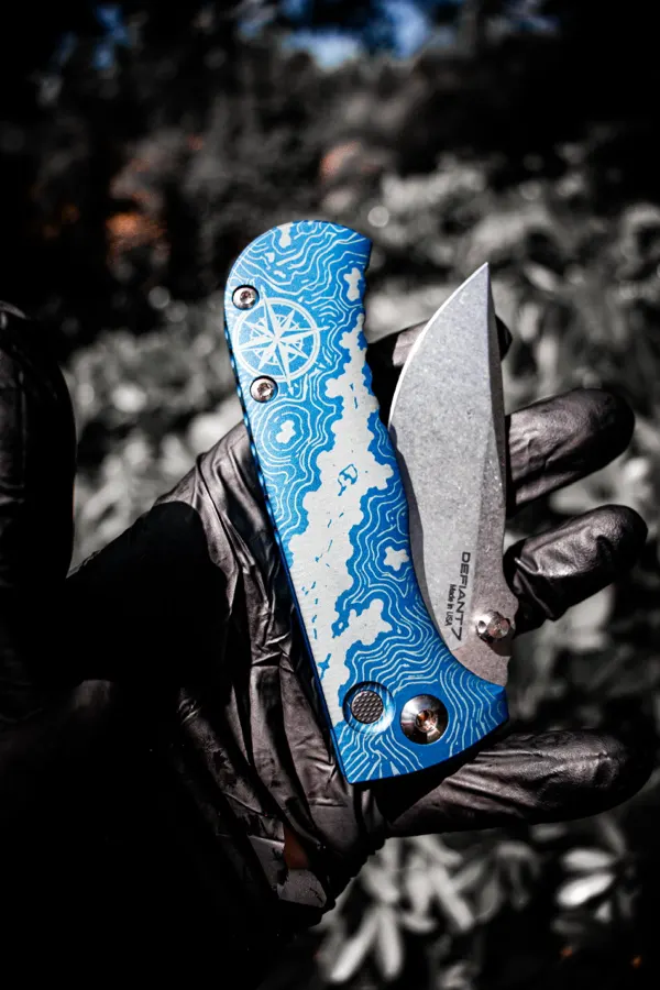 Custom blue damascus folder held in a work glove